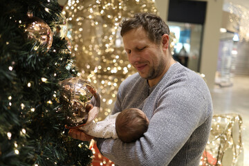 Father holding his newborn baby near the Christmas tree