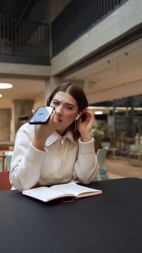 Vertical screen woman listens to a voice reply from artificial intelligence holding her phone with a displeased expression as the answer does not satisfy her creating a moment of doubt and frustration