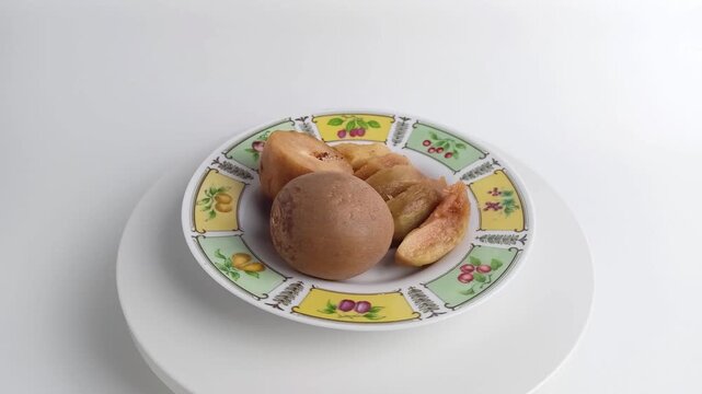 Sliced and whole sapodilla fruit served on plate rotating. Fresh sweet tropical chiku for healthy dessert. Organic food on white background.
