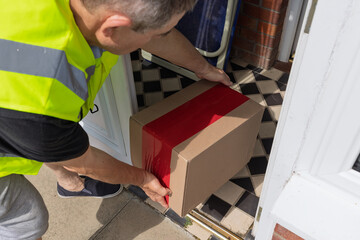 Courier placing parcel inside open porch doorway high-angle view