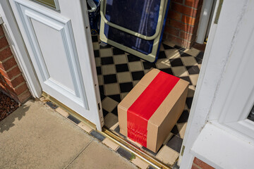 Online shopping parcel delivery left inside open porch doorway from outside