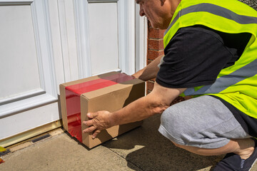 Courier delivering online shopping parcel to home doorstep with white door