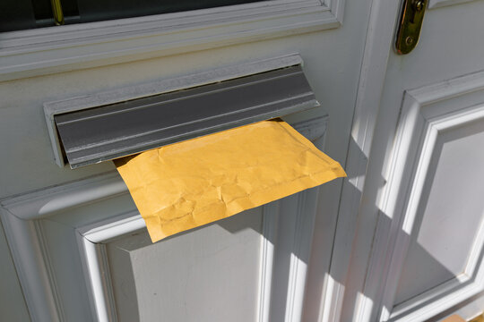 Padded Envelope Online Shopping Delivery Stuck in Letterbox of Modern Front Door
