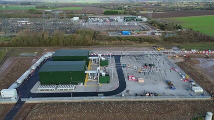 Aerial drone view of an extensive substation with transformers, high voltage lines, synchronous condensers and solar energy panels near Wisbech England