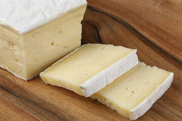 Brie cheese. Pieces cut on a cutting board.