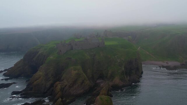 Dramatic aerial shot of the medieval Dunnottar Castle ruins on a cliff overlooking the North Sea