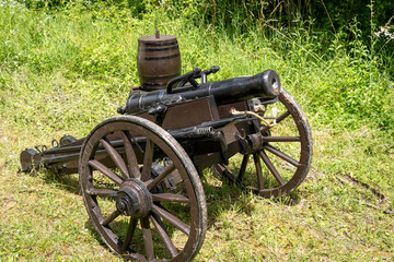 Fototapeta premium Historical field cannon on a wooden carriage with gunpowder barrels on a natural background