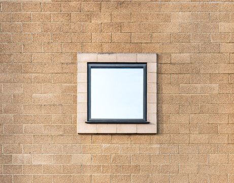 square mirror reflective window centred on an orange brick wall