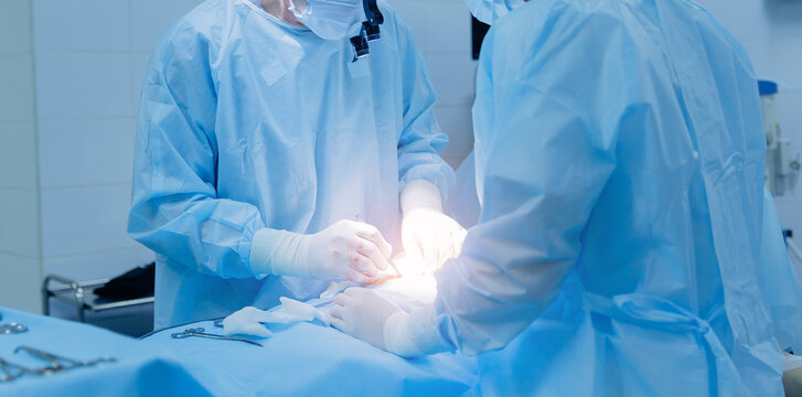 Asian female surgeons performing surgery in operating room with precision, umbilical hernia removal