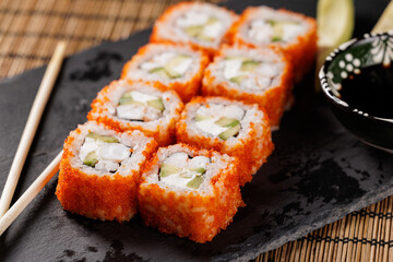 Japanese cuisine delight: california rolls with crab, avocado, and tobiko on slate, top view