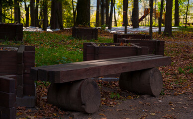 Rustic wooden bench in autumn forest park with fallen leaves