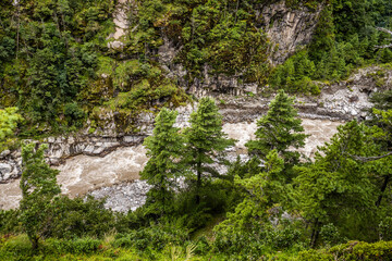 Bhote koshi river full of dirty, muddy water after monsoon flowing in narrow gorge. Top view from the Hillary bridge on Everest base camp trekking. Khumbu, Nepal.