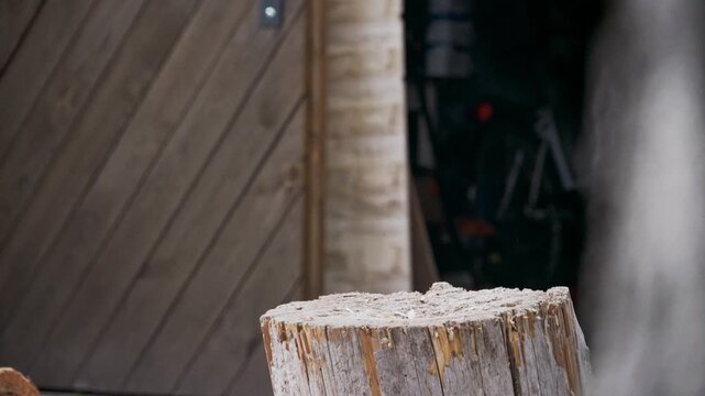 Dynamic close-up shot of an axe splitting a log, with wood shards flying in motion. Powerful moment of manual labor, forestry work and firewood preparation captured in action outdoors.