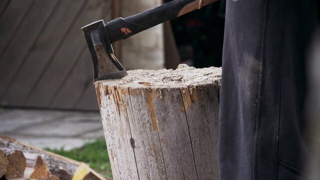 Close-up of an wooden chopping block with axe as a person prepares firewood. Rustic outdoor scene highlighting manual labor, wood cutting, and traditional craftsmanship in the countryside.