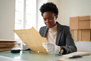 Archivist preserving historical documents at conservation station, gloves on