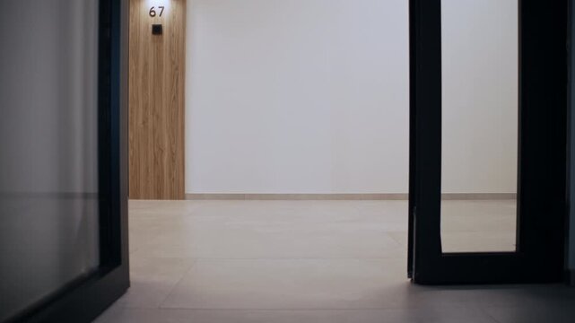 An AI-powered robotic courier walks down a hallway in a contemporary apartment building, demonstrating fully automated package delivery without human intervention.