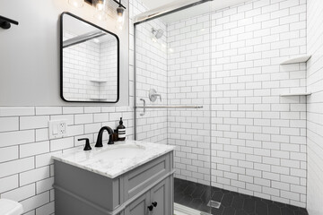 A bathroom with a grey cabinet with a white subway tile backsplash and tiled shower with a glass...