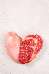 Heart shaped raw meat cut with chicken breast and beef steak placed on a white surface ready for cooking, showing different textures and colors of the meats