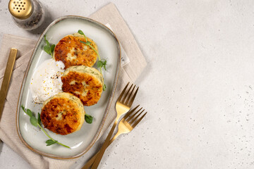 Delicious cottage cheese syrnik cakes served with yogurt and herbs on a simple plate during lunch time