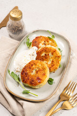 Delicious cottage cheese syrnik cakes served with yogurt and herbs on a simple plate during lunch time