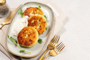 Delicious cottage cheese syrnik cakes served with yogurt and herbs on a simple plate during lunch time