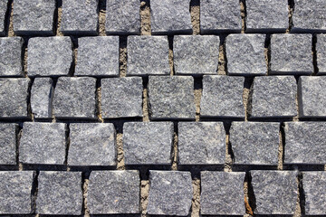 Paving the road with square granite stones.