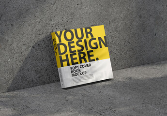 Square Softcover book mockup stands leaning against the wall