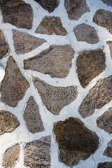 Close-up view of an irregular masonry wall composed of textured natural stones and light mortar joints. 