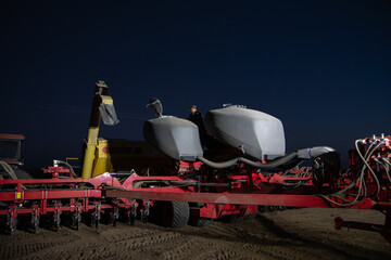 Operario preparando semillas en sembradora para sembrar soja en campo de noche