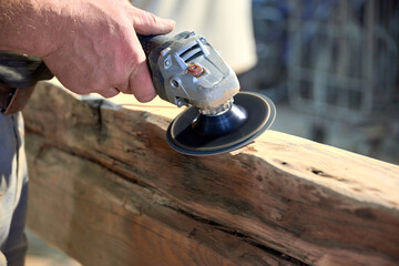 Worker Sanding Wooden Beam with Power Tool