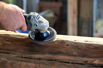 Worker Sanding Wooden Beam with Power Tool