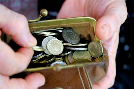 An elderly retired woman holds a wallet full of Turkish coins. Turkish lira. 5 kuruş, 10 kuruş, 50 kuruş, 1 TL., 5 TL. Economic crisis. Inflation. Loan debt. Pensioner salary increases. Retirement.