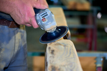 Worker Sanding Wooden Beam with Power Tool
