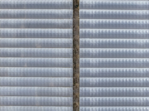 Aerial view of the corrugated metal surfaces, reflecting the muted sunlight in geometric patterns, casting subtle shadows across the industrial landscape, Battipaglia, Campania, Italy.
