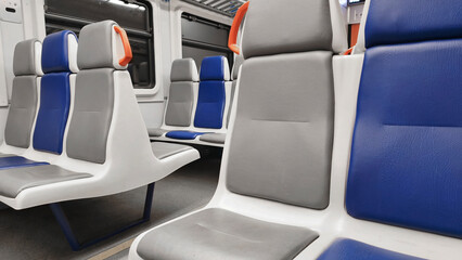 Modern train interior featuring clean seats in gray and blue with minimalistic design. Public transportation seating area with contemporary colors and bright LED lighting.
