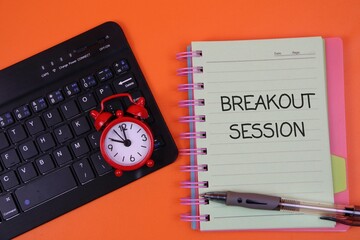 a black keyboard, notebook labeled "Breakout Session", a red alarm clock, and a pen on a orange surface. Conveys focus, planning, and time management.