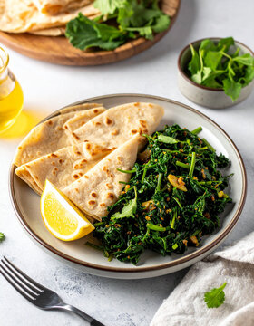 A plate of Eritrean hamli saut�ed greens is served with injera and a wedge of lemon.