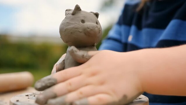 Child Creating Cat Sculpture with Clay in Outdoor Setting