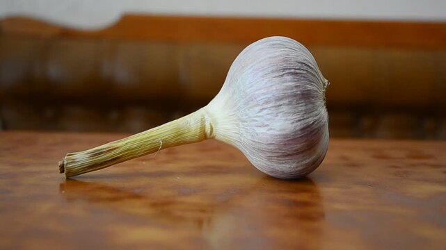 A head of garlic on a dark background shows the product of camera movement mushroom on a wooden board