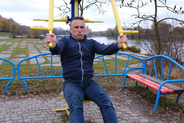 Athletic young man performing arm exercises with dumbbells on outdoor track. Engaging in strength training activities with focus and determination. High quality photo