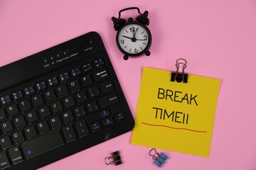 a keyboard, a yellow sticky note reading "BREAK TIME", an analog clock, and small binder clips on a pink background. Evokes focus, pause, and a timely break.