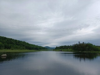 a sleepy overcast day over Canada lake casting a silvery reflection on the dark lake water.