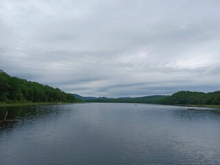 a sleepy overcast day over Canada lake casting a silvery reflection on the dark lake water.