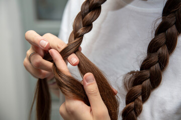 Naklejka premium młoda dziewczyna czesze włosy i plecie warkocze