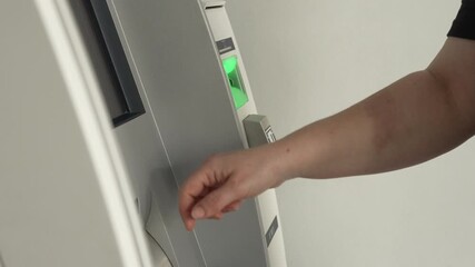 Hand touching ATM touchscreen at banking terminal as person selects options on screen near green card slot for electronic payment and cash withdrawal concept