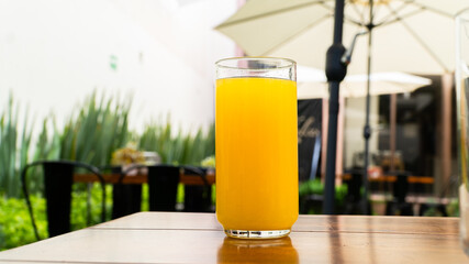 Vasos con agua de limón y jugo de naranja sobre mesa de madera / Glasses with lime water and orange juice on wooden table