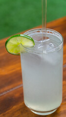 Vasos con agua de limón y jugo de naranja sobre mesa de madera / Glasses with lime water and orange juice on wooden table