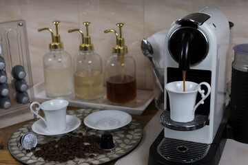 Coffee brewing scene with home coffee machine, coffee pods and flowing coffee
