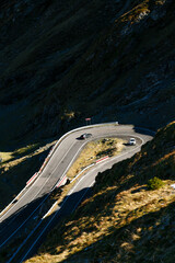 Cars driving through sharp mountain hairpin turn on Transfagarasan Highway in Romania.
