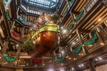 London, UK, An upward view of the &ldquo;Good Ship Liberty&rdquo; Christmas installation, a large wooden ship suspended in Liberty London&rsquo;s timber-framed atrium, adorned with festive garlands and lights.